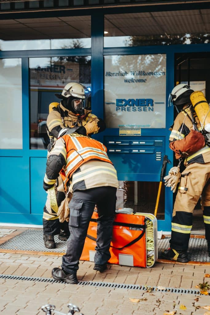 Feuerwehrleute mit Atemschutz vor Eingang EXNER Pressen