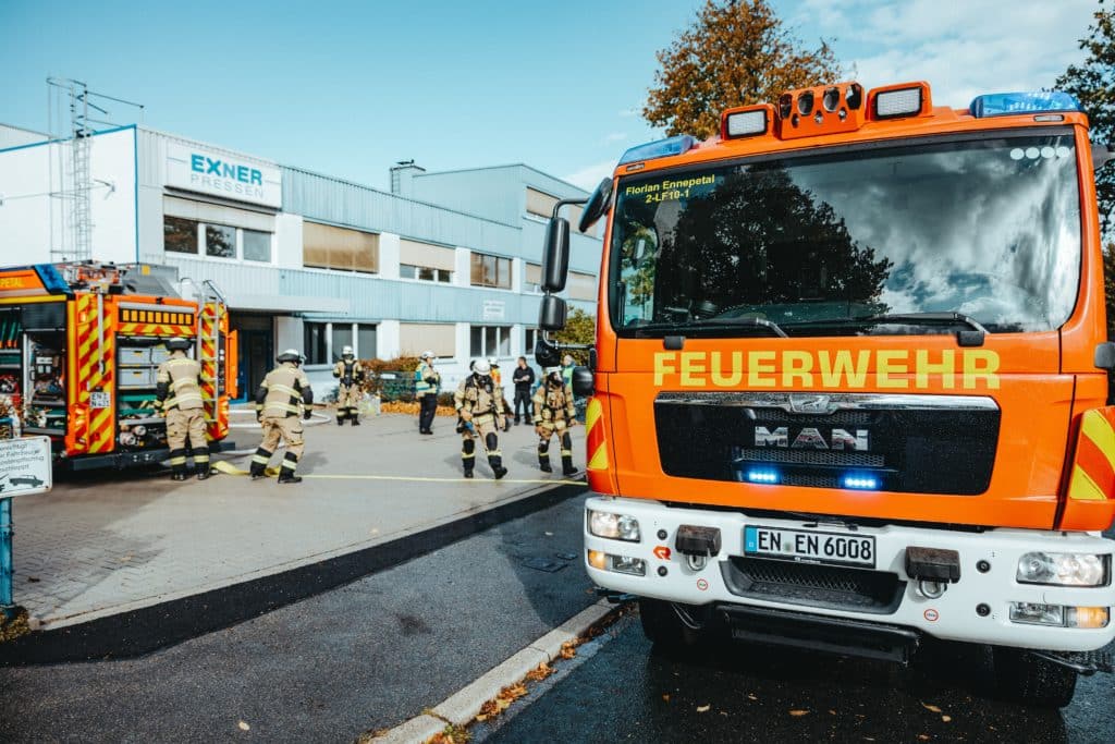 Feuerwehrfahrzeuge und Einsatzkräfte vor EXNER Pressen bei Übung